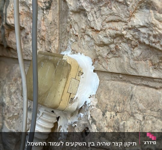 שקע חשמלי מותקן על קיר אבן עם חוטים